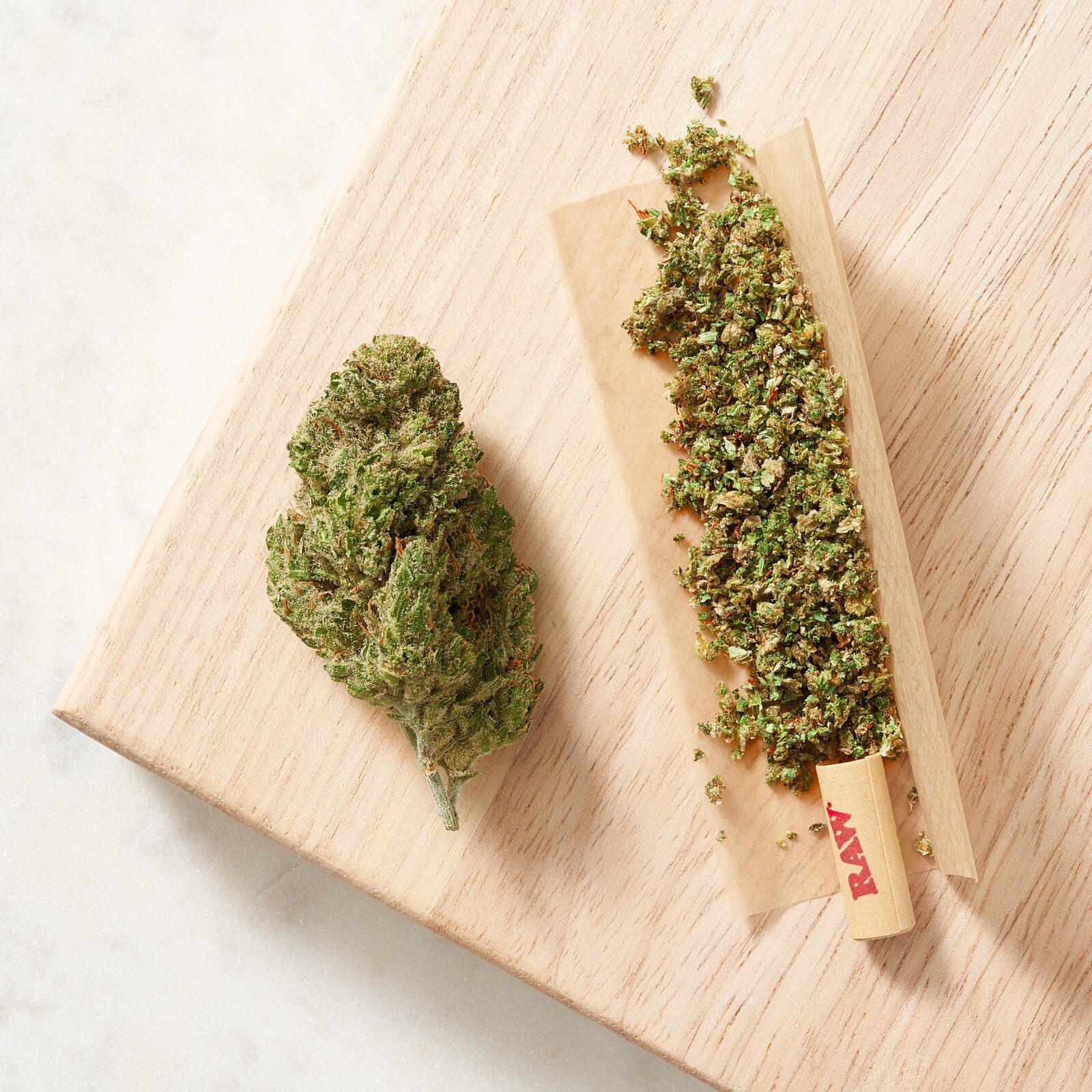 THCA flower, whole and ground, on a wood board